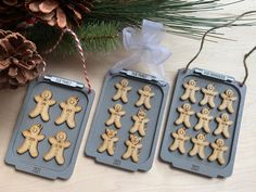 three cookies in the shape of gingers on a tray next to pine cones and a christmas ornament