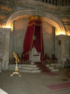 the interior of a castle with red drapes and gold decorations