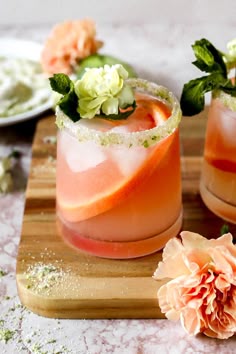 two cocktails on a cutting board with flowers