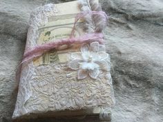 an old book covered in lace and fabric with a flower on the front, sitting on a bed