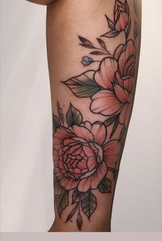 a woman's leg with flowers and leaves tattooed on the side by her arm