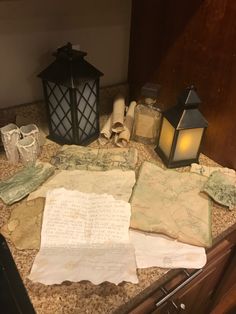 an assortment of items on a counter top with a lantern, paper and other items