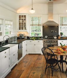 a kitchen with wooden floors and white cabinets, black counter tops, and wood flooring