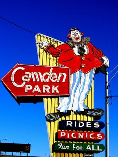 a sign for a garden park with a clown on it's side and a red sign that says rides picnics fun for all