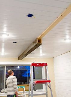 a man that is standing on a ladder in front of a ceiling with some lights