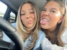 two women sticking out their tongues in the back seat of a car