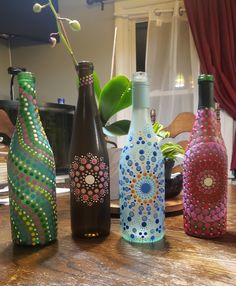 four painted bottles sitting on top of a wooden table