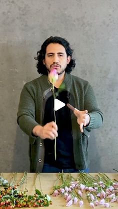 a man standing in front of a table with flowers on it and holding a knife