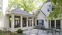 a patio with chairs and tables in front of a white house