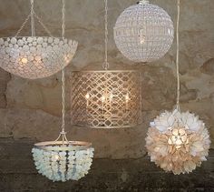 four hanging lights made out of shells on a stone wall next to a brick wall