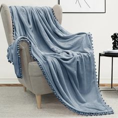 a chair with a blanket on top of it in front of a wall and a painting