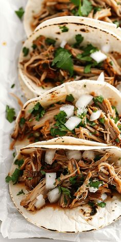 three shredded pork tacos with cilantro and onions