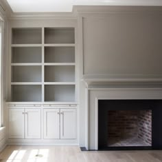 an empty living room with built in bookshelves and fireplace