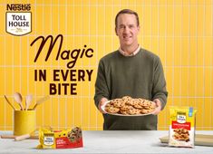 a man holding a plate of cookies in front of a yellow wall with the words magic in every bite