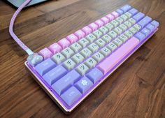 a pink and purple keyboard sitting on top of a wooden table