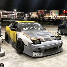 a car parked in a parking lot next to another car with writing on the hood