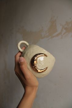 a hand holding a cup with a gold moon on it