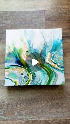 an abstract painting is displayed on a wooden surface with a video player playing the game