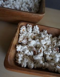 two wooden bowls filled with popcorn on top of a table