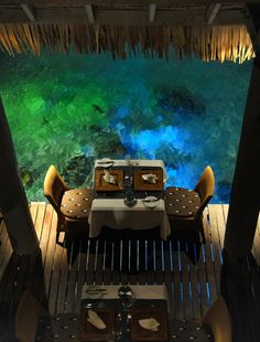 an outdoor dining area with table, chairs and view of the water from above it