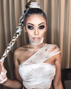 a woman in white dress with braids on her head and makeup applied to look like an egyptian queen