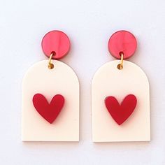 two pairs of red and white earrings with a heart cut out on the back of them