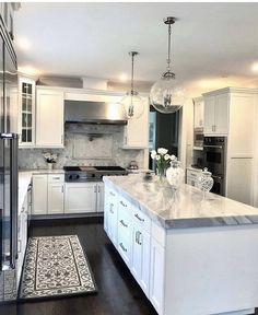 a large kitchen with white cabinets and marble counter tops