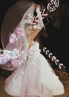 a woman in a white dress and veil with lights on her head is posing for the camera