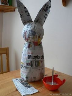 a newspaper bunny sitting on top of a wooden table