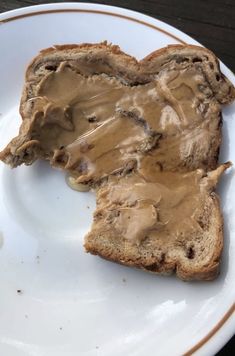 two pieces of bread with peanut butter spread on them, sitting on a white plate