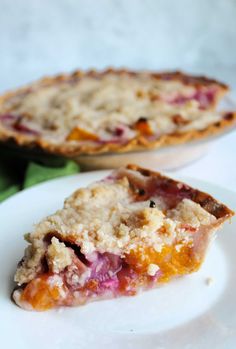 a piece of rhubarb pie on a plate with the rest of the pie in the background