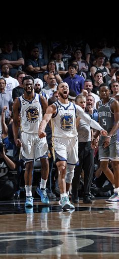 two basketball players are walking on the court with their arms in the air as people watch