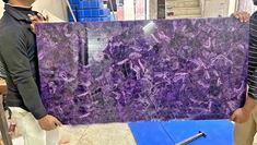 two men holding a large purple marble slab