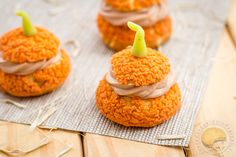 three orange crochet cupcakes with frosting and a candle on top