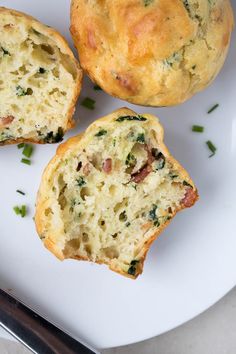 three muffins sitting on top of a white plate next to a knife and fork