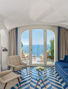 a living room filled with furniture and a large window overlooking the ocean in front of it