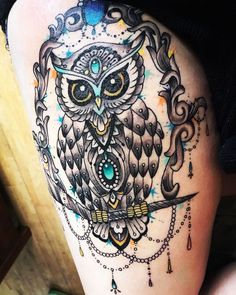 an owl tattoo on the thigh with chains around it's neck and eyes,