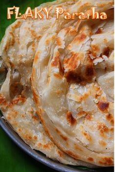 three flat breads sitting on top of a metal pan with the words flaky paratha