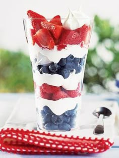 yogurt with berries and blueberries in a small glass dish on a white surface