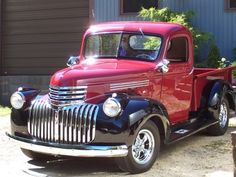 an old red truck parked in front of a house