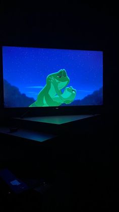 a large screen tv sitting on top of a table in the dark with a cartoon character