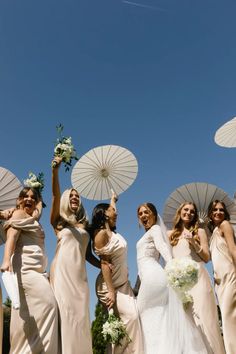 a group of bridesmaids holding umbrellas in the air