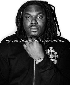 a man with dreadlocks standing in front of a white wall wearing a black jacket