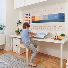 a little boy sitting at a desk with a calendar on it