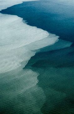 an aerial view of the water and land in the ocean, with ice floes