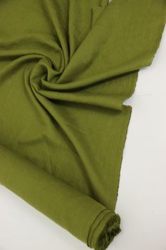 the green fabric is folded on top of the white surface