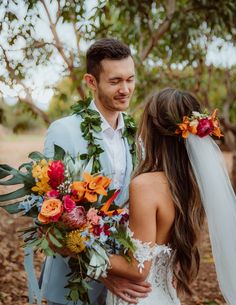 a bride and groom standing together in front of trees with flowers on their foreheads