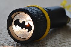 a flashlight with a batman symbol on the front is laying on the floor next to a flower