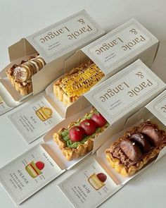 four boxes with different types of food in them sitting on a table top next to each other