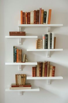 three white shelves filled with books on top of each other